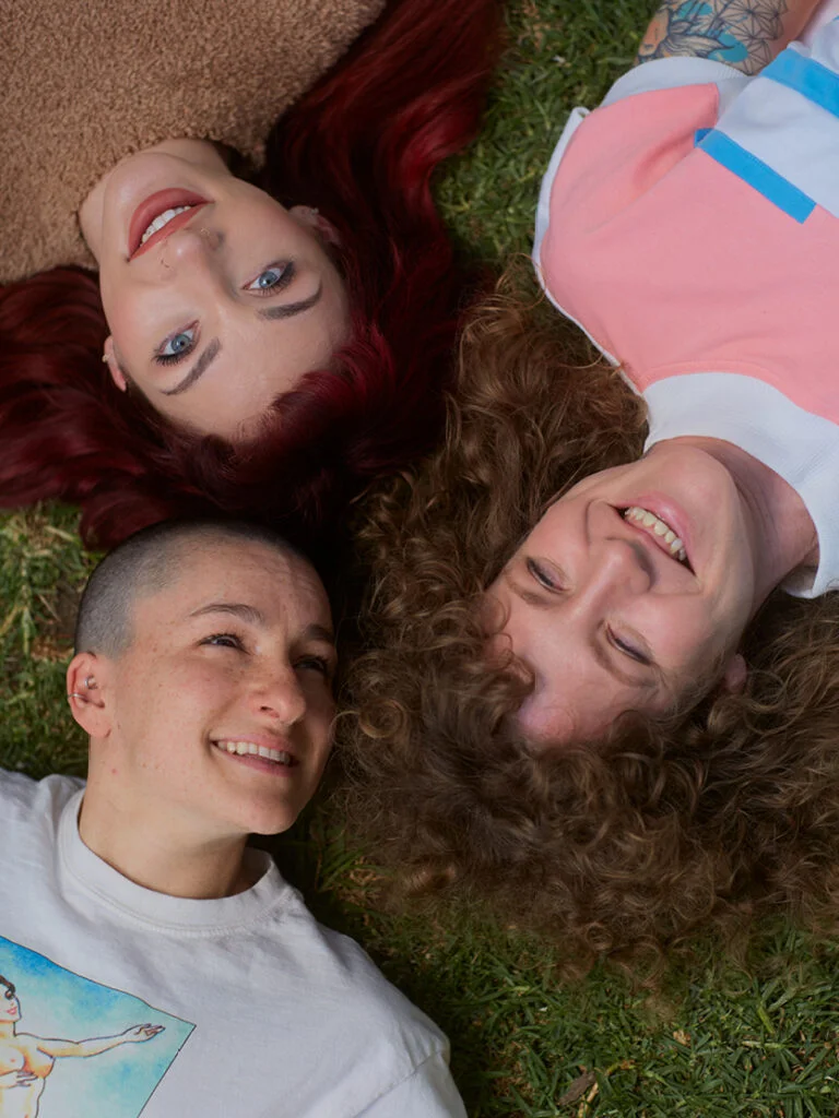 Two people smiling and laying together outdoors—symbolizing the connection, joy, and intimacy inspired by Looking for Each Other’s fragrances and mission.
