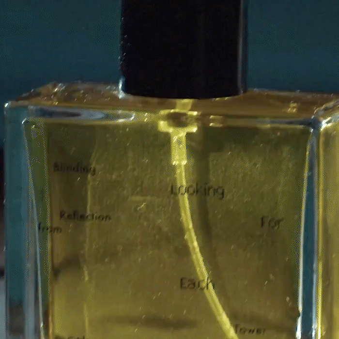 Close up looping video of a wet hand coming out from a pool grabbing a bottle of Blinding Reflection from Tower Window by Looking for Each Other, catching soft amber light. The minimal glass design and golden liquid highlight the brand’s commitment to clean, botanical-only perfumery.